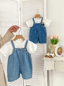 Detail of infant summer set with bear print denim overalls and white t-shirt on hanger