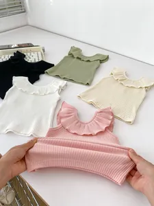 Detail showing high elasticity of children's ribbed ruffle tank top in five soft colors