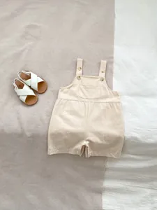Close-up of cotton linen baby romper showing shoulder buttons and front pocket detail