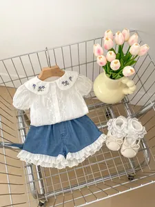 Detail der weißen Mädchen-Baumwollbluse mit Peter-Pan-Kragen und blauer Stickerei