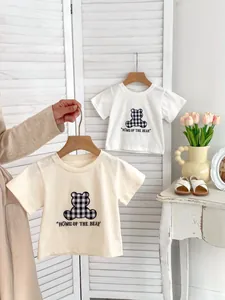 Detail of baby cotton t-shirts with plaid bear print in white and beige colors