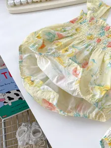 Details des gelben Baby-Bodys mit Blumenmuster, Rüschen und Druckknöpfen im Schritt