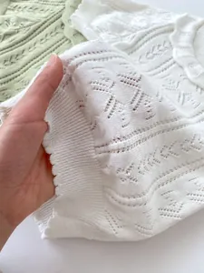 Close-up of baby girl knitted shirt featuring hollow crochet texture and wavy hem