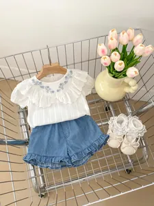 Detailaufnahme der Baby Mädchen Baumwollbluse mit blauer Blumenstickerei und Rüschenkragen