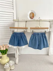 Detail of girls denim shorts featuring white lace embroidery and elastic waistband