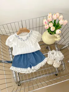 Detail der Babymädchen-Baumwollbluse mit Blumenstickerei und spitzenbesetzten Jeansshorts