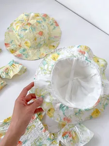 Details von Baby-Sonnenhüten und Stramplern mit zarten Aquarell-Blumenmustern