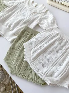Detail of baby knit set featuring hollow texture and delicate ruffle collar design