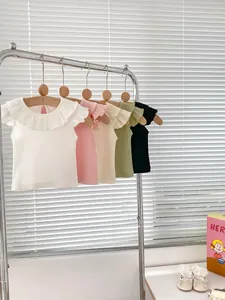 Close-up of ruffled collars and ribbed cotton fabric on colorful baby girl summer t-shirts