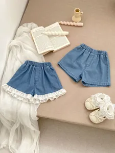 Detail of light blue denim shorts for girls featuring delicate white lace trim on the hem
