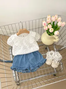 Flachbild von weißem Baumwolltop mit Stickerei und Denim-Shorts mit Rüschen für Mädchen