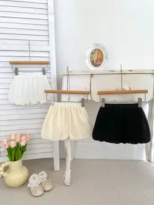 Close-up of three cotton linen bubble shorts in white, cream, and black on wooden hooks