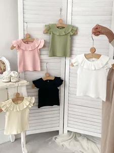 Detailed view of baby ribbed knit shirts with ruffled collars in five pastel colors