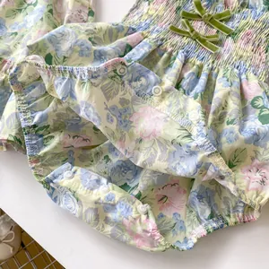 Vue détaillée du barboteuse fleurie pour bébé avec boutons-pression et nœuds velours