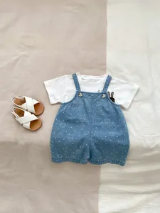 Flat lay of baby summer set with white T-shirt and bear print denim overalls