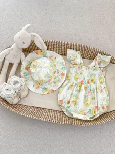 Flachbild von Baby-Body mit Blumenmuster, passendem Sonnenhut und Spitzenschuhen im Korb