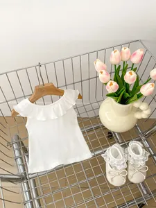 Detail of white sleeveless ruffled top for girls with lace bow baby shoes in a cart