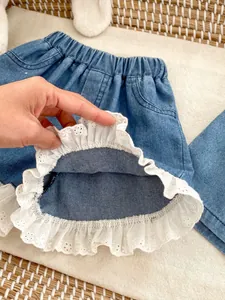 Detail shot of girls denim shorts showing the white eyelet lace hem and stitching