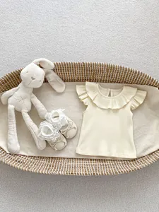 Detail of cream ribbed knit baby top with ruffled collar and matching lace bow shoes