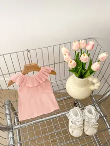 Detail of baby girl pink knit sleeveless top with ruffles and lace floral shoes