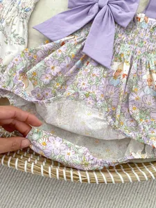 Detail of floral baby bodysuit featuring a large purple bow and snap button closure