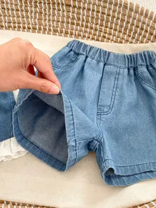 Detail of baby denim shorts featuring white lace trim and comfortable elastic waistband