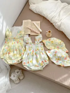 Flachbild von Baby-Blumen-Stramplern mit passenden Hüten und Zubehör auf einem Bett