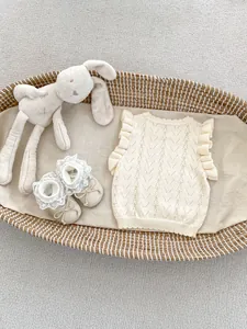 Detalle de chaleco de punto para bebé con volantes y zapatos de encaje a juego en cesta
