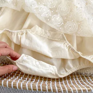 Detail view of baby bodysuit with resin snap buttons and delicate floral lace mesh fabric