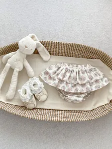 Detailed view of floral ruffle baby bloomers and lace newborn shoes in a cozy basket
