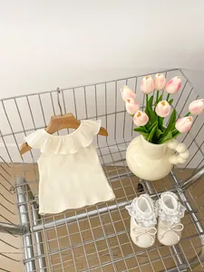 Detail of baby girl sleeveless ruffle top and lace shoes in a metal shopping basket
