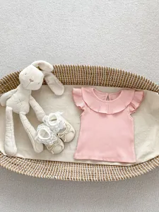 Detail of pink ribbed baby shirt with ruffle collar and butterfly sleeves in a basket