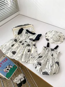 Flat lay of baby summer outfit set featuring black floral dress, bodysuit, and sun hat