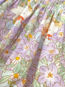 Close-up of floral cotton fabric with cartoon prints and ruffled texture for baby romper