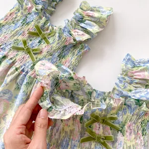 Détails de robe à fleurs pour bébé avec smocks délicats et nœuds en velours vert