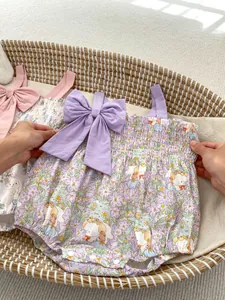 Detail of floral baby bodysuit featuring elastic smocking and large bow accents