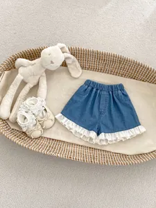 Detail der Mädchen-Denim-Shorts mit zartem weißen Spitzenbesatz und floraler Bestickung