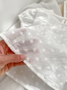 Detailansicht der weißen Mädchenbluse mit Baumwollstickerei und feiner Textur