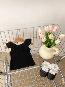 Detailed shot of black ruffled sleeveless top and leather baby shoes in a wire basket