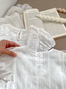 Detailansicht von Baby-Oberteilen mit feiner Stickerei und Plissee-Struktur am Rücken
