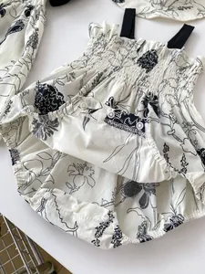 Close-up of cotton floral baby romper with smocked chest and snap buttons for diapering