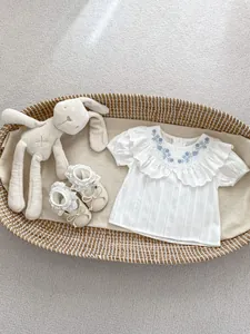 Detailansicht einer weißen Baby-Mädchenbluse aus Baumwolle mit besticktem Rüschenkragen