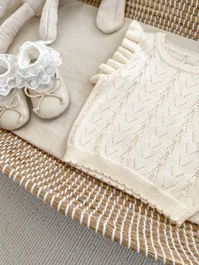 Detalle de chaleco de punto para bebé con volantes y zapatos suaves de encaje a juego