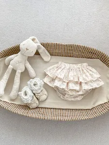 Close-up of floral ruffle baby bloomers and matching lace infant shoes in a basket