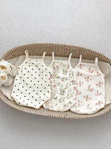 Three-pack cotton baby bodysuits with rabbit and floral prints in a woven basket
