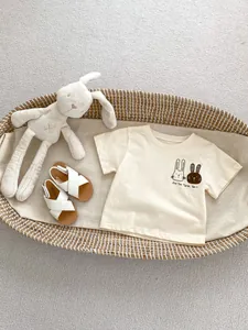 Dettaglio maglietta neonato in cotone con stampa coniglio in cesto decorativo