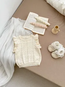 Detalle de chaleco de punto para bebé con patrón calado y mangas con volantes