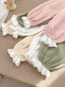 Détail du pantalon en gaze de coton bébé avec dentelle en rose, vert, jaune et blanc