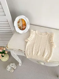 Detalle del chaleco de punto crema con diseño de calados en V y volantes en los hombros