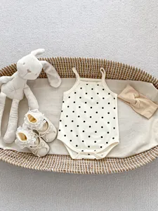 Flat lay of polka dot baby romper with lace princess shoes and a knotted headband